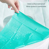 A teal disposable toilet seat cover is shown being placed on a white toilet seat.