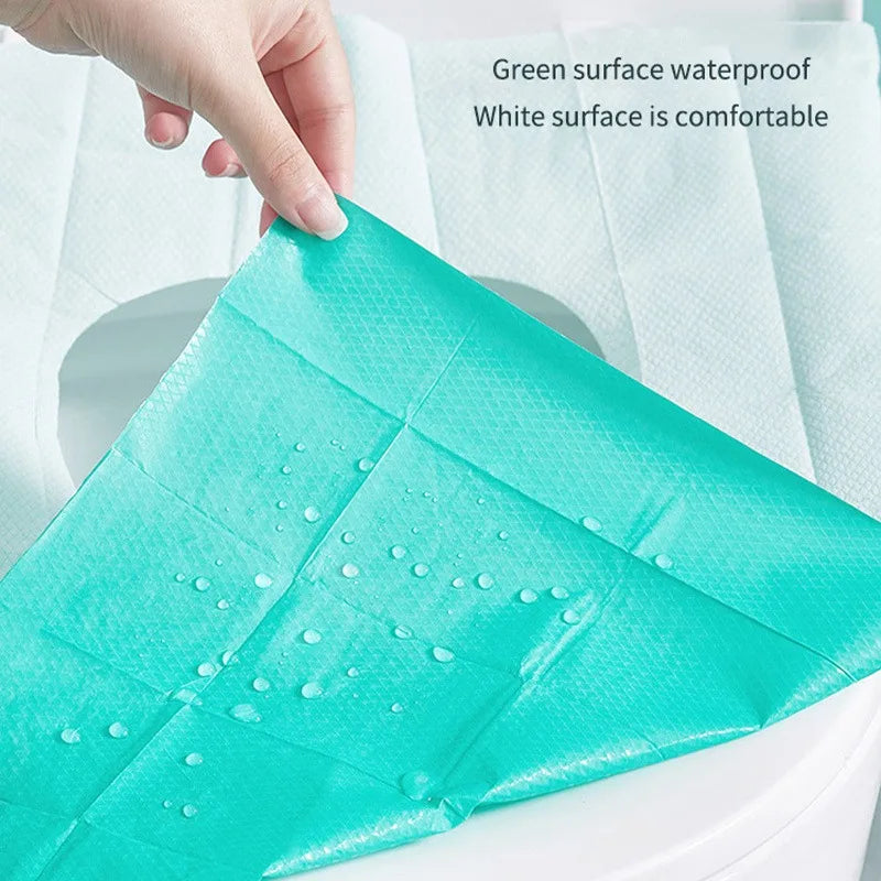 A teal disposable toilet seat cover is shown being placed on a white toilet seat.