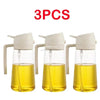Three clear glass oil spray bottles with white pump tops and yellow oil inside
