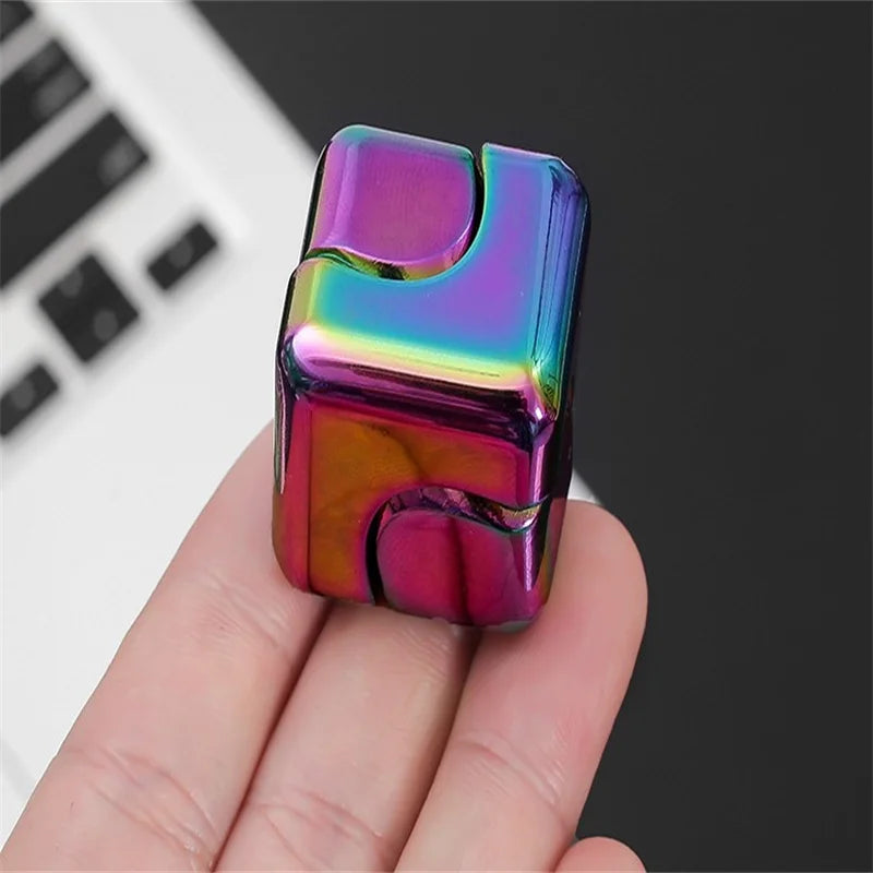 A vibrant, iridescent metal fidget spinner cube is held in a hand against a dark background.