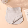 A light beige, quilted baby burp cloth is shown flat on a pink background.