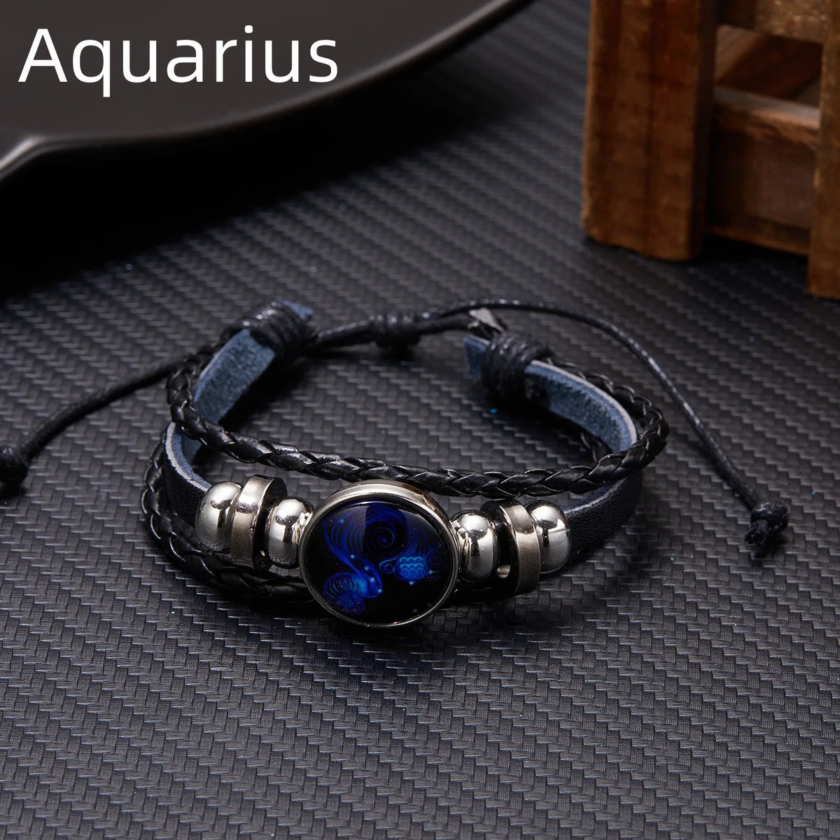 A black leather wrap bracelet featuring a blue glow in a silver charm, suitable for an Aquarius zodiac sign.