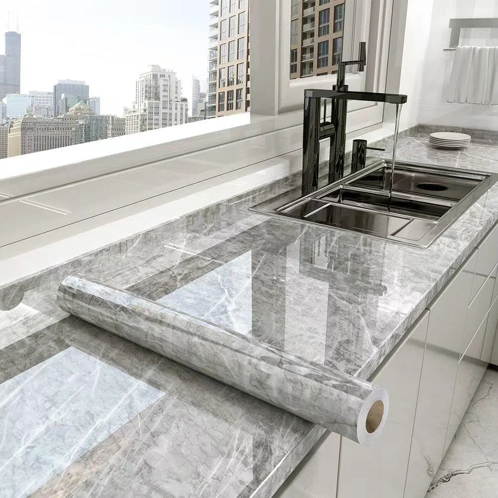 A marble effect self-adhesive PVC film is shown on a kitchen countertop, used for decorating cabinets and countertops.