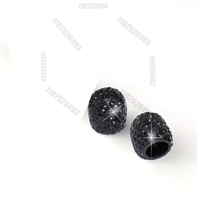 A close-up view of a black crystal-cut tire valve cap with a shiny, faceted surface.