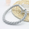 Silver rope magnetic curtain tiebacks with a metal clasp resting on a woven mat