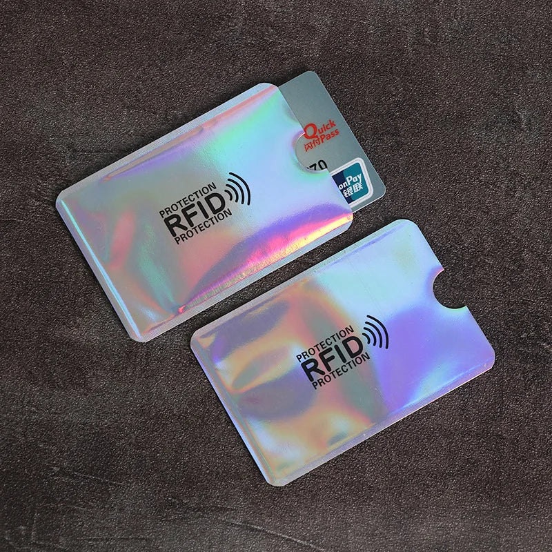 A set of ten plastic RFID blocking card sleeves with a rainbow iridescent finish are displayed on a dark brown surface.