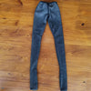 A pair of dark gray, sheer stockings or tights lying flat on a wooden surface.
