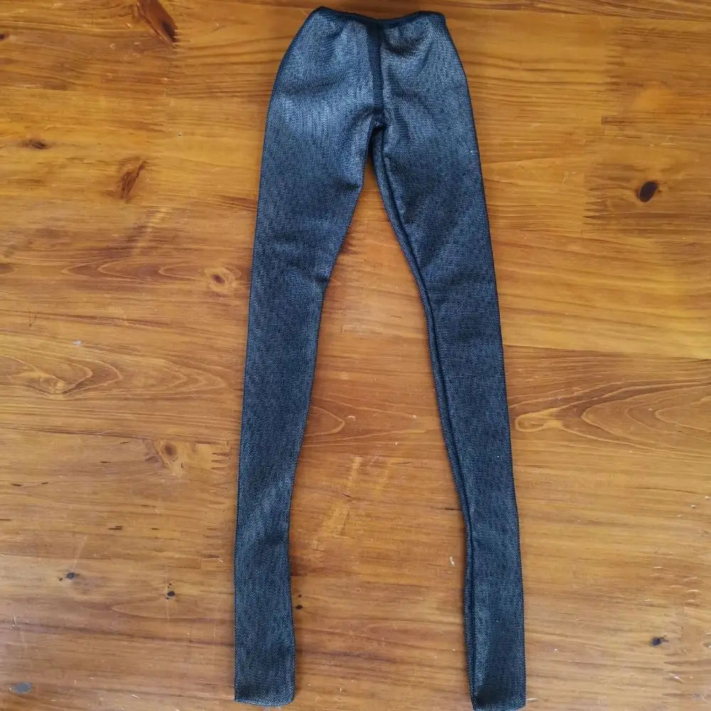 A pair of dark gray, sheer stockings or tights lying flat on a wooden surface.