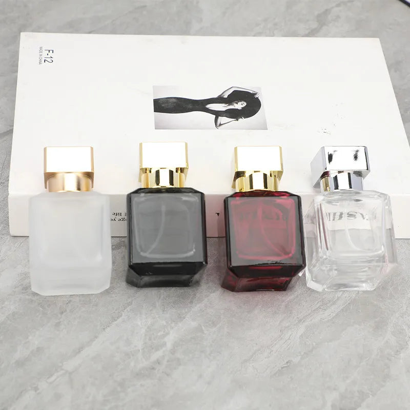 A row of four elegant glass perfume bottles with gold sprayers and a black silhouette graphic on the packaging.