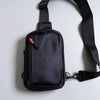 A black compact water-resistant sling bag with a strap is shown against a light gray background.
