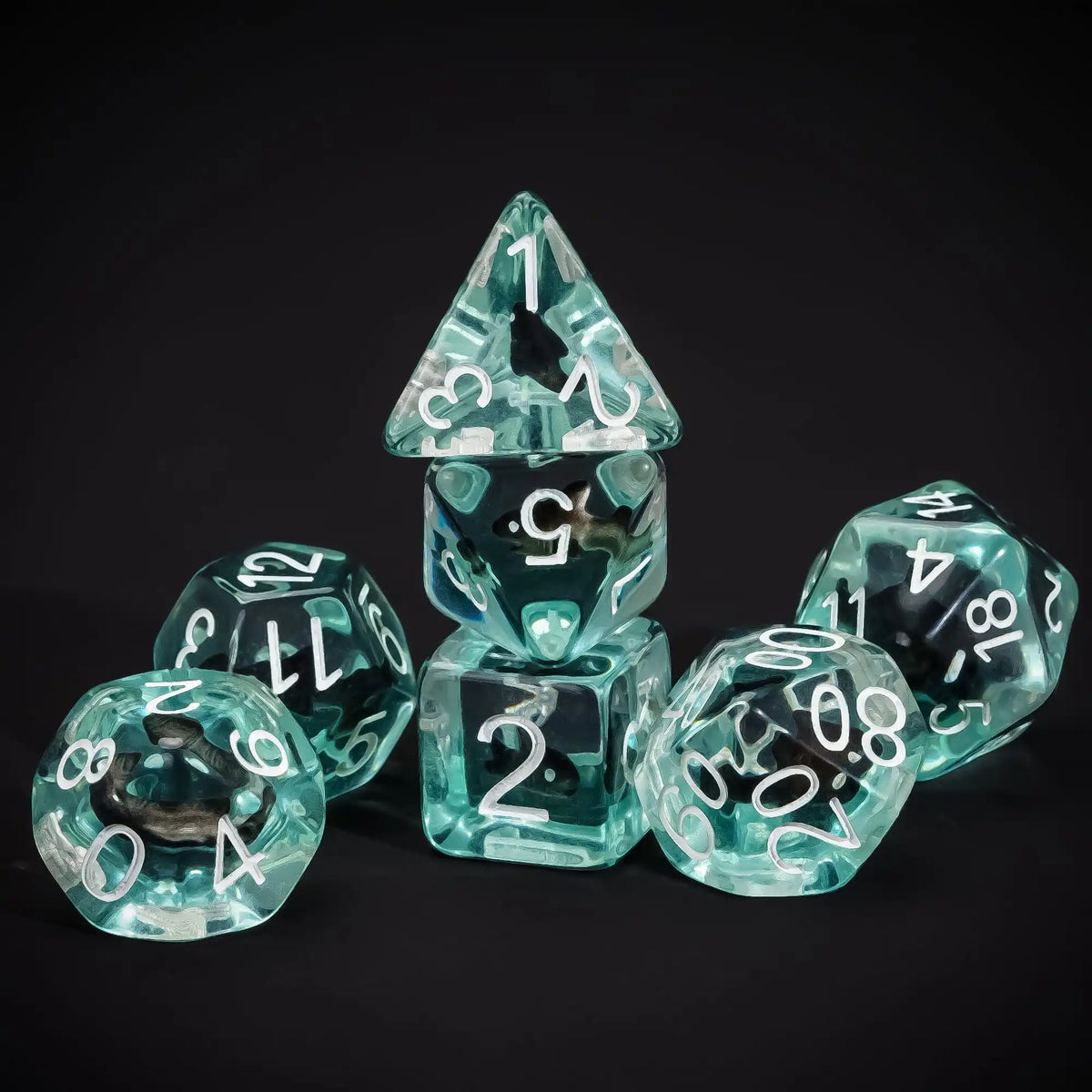 A set of clear teal resin dice shaped like pyramids and dodecahedrons for tabletop role-playing games