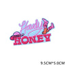 Pink and orange embroidered letter patches spelling 'Howdy Honey'