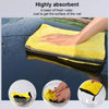 A yellow highly absorbent microfiber cleaning towel soaking up water on a dark surface.
