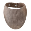 A round, beige organic cotton muslin baby bib with a gathered top and absorbent band.
