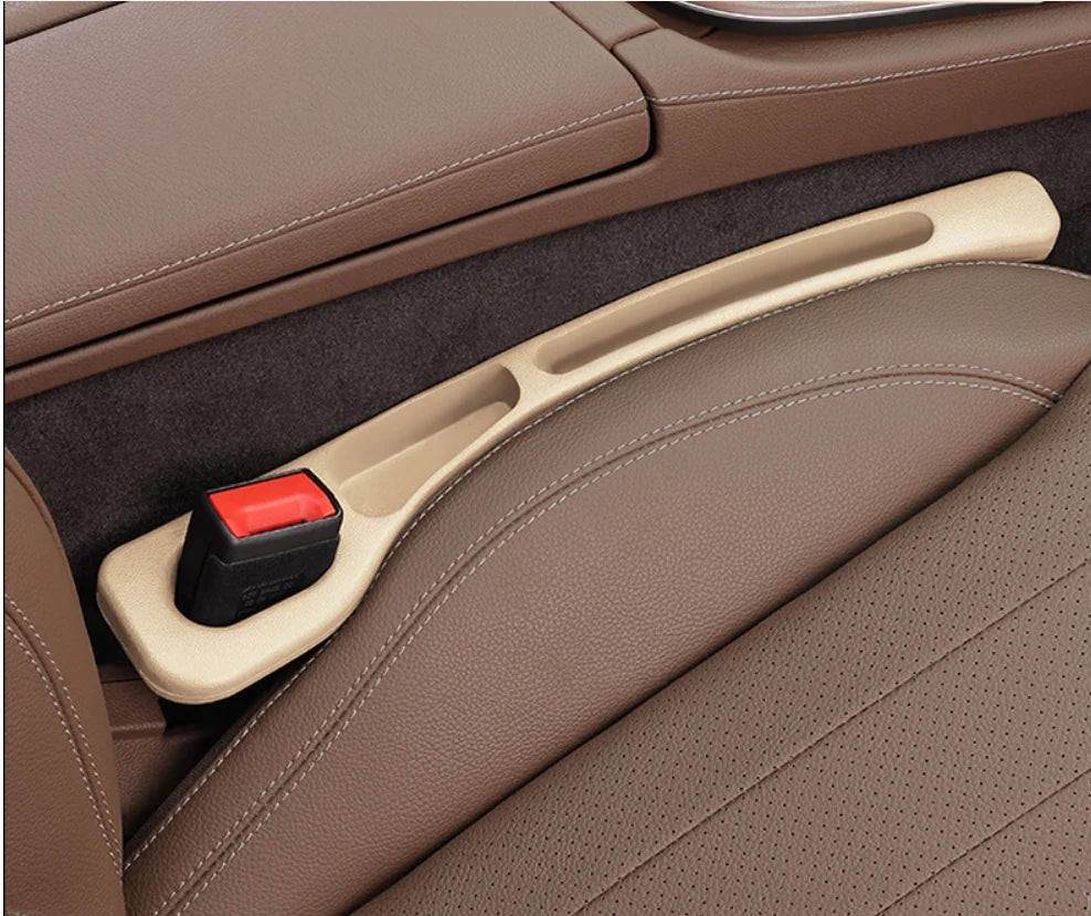 A beige car seat gap filler and organizer is shown inside a brown leather car seat.