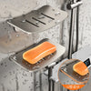 Aluminum wall-mounted soap dish with drain featuring an orange soap bar and U-design.
