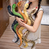 A girl is holding several lifelike snake plush toys of various colors and patterns.