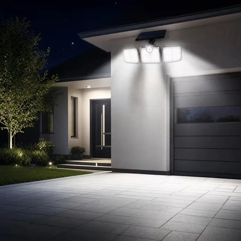 Exterior view of a modern house featuring a 4-head solar motion sensor flood light illuminating the driveway.