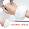 A hand is washing its arm with a white, absorbent wristband or scrunchie to prevent liquids from spilling down the arm.