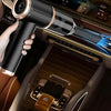 A hand holds a powerful cordless handheld vacuum with a long tube and blue light, positioned near a car's interior controls.