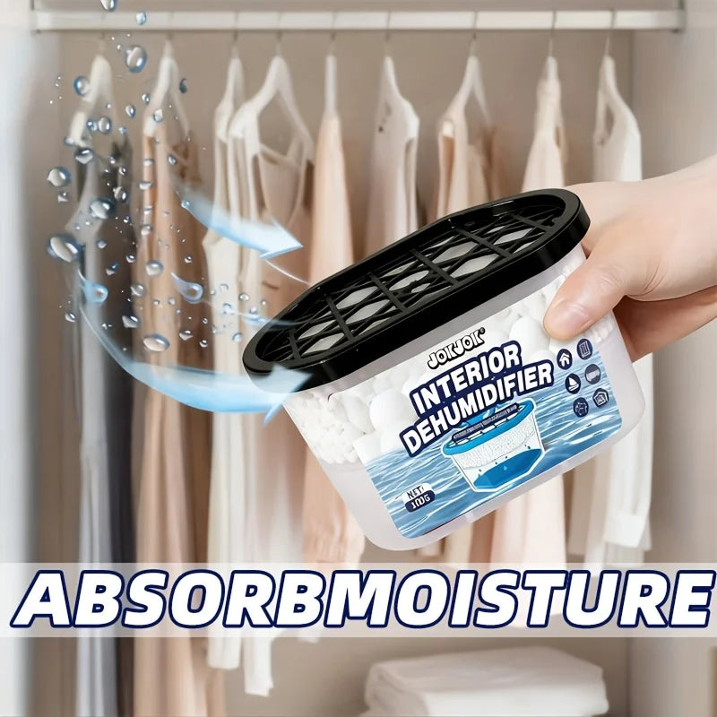 A hand holds a white moisture absorber box with a black lid, demonstrating its use to remove moisture from clothing.