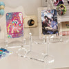 Clear acrylic display stand holding a photo and card, next to a camera and other accessories.