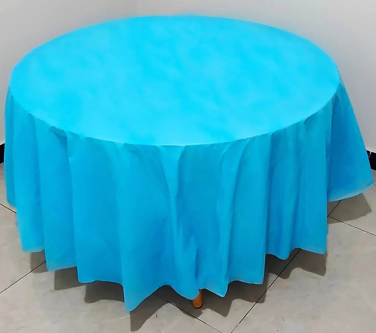 A vibrant light blue disposable round tablecloth spread over a table.