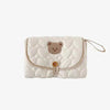 A white quilted foldable portable diaper changing pad with a brown bear face design.