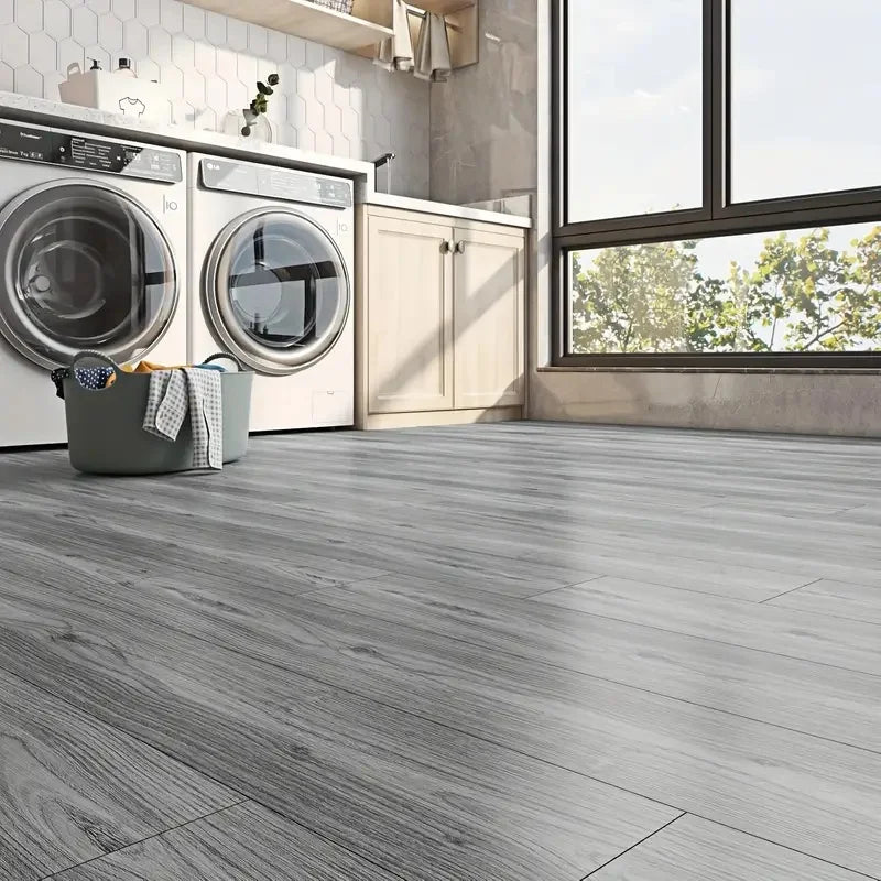 Gray wood grain PVC self-adhesive decals on a floor in a modern laundry room.