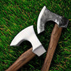 A hand-forged Viking tomahawk axe resting on vibrant green grass.