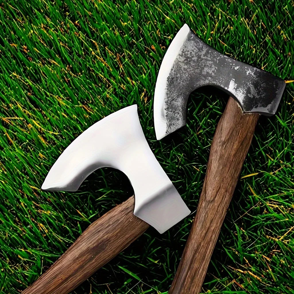 A hand-forged Viking tomahawk axe resting on vibrant green grass.