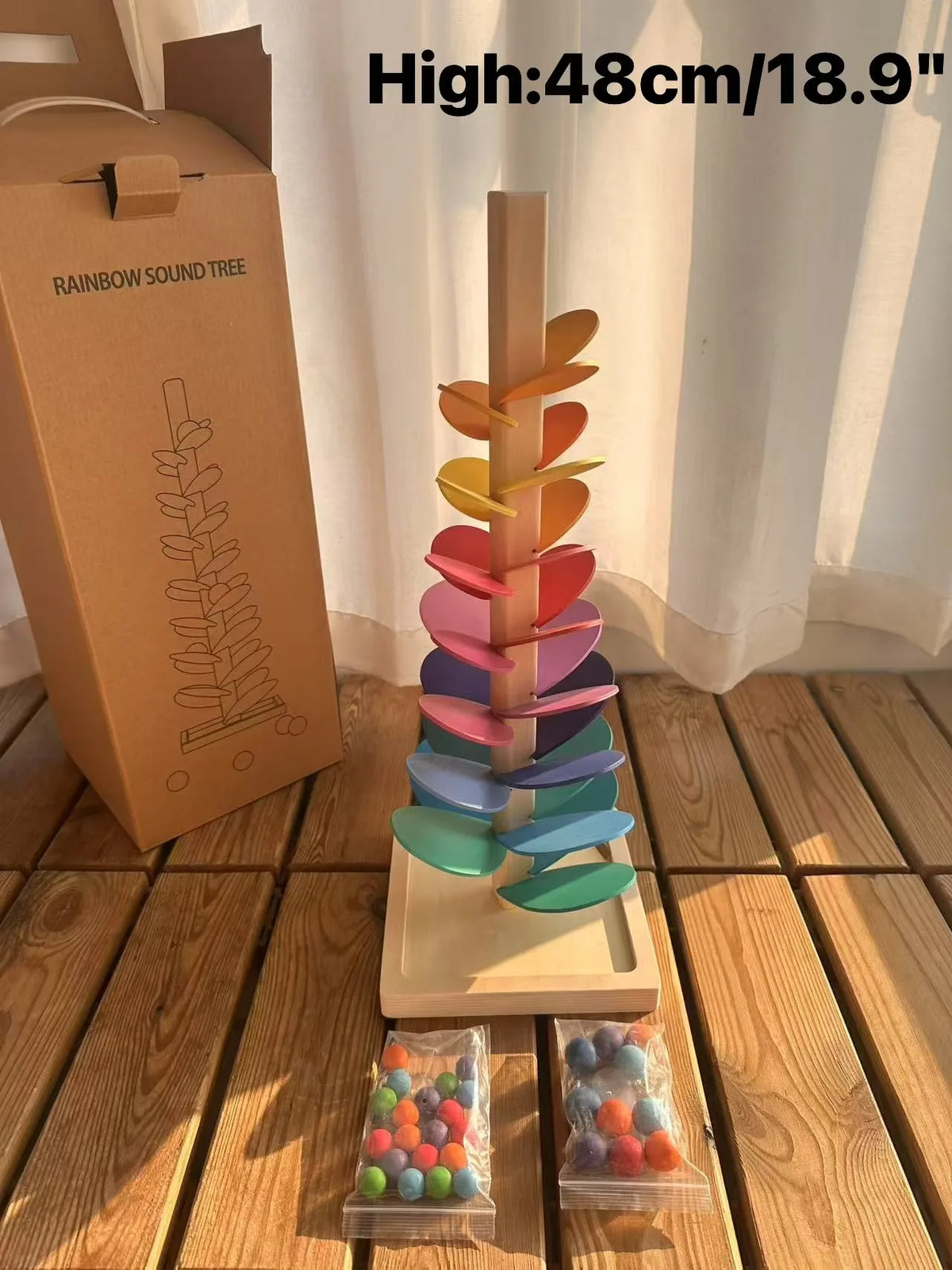 Holzregenbogen-Soundbaum mit farbenfrohen Blüten und einer Marmorschlange auf Holzoberfläche.