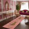 A pink runner rug with a gold leopard print design on a dark wood floor in an elegant room.