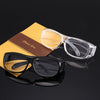 A pair of clear plastic reading magnifying glasses resting on a yellow card with brown text.
