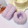 A fluffy lavender microfiber wrist sweatband and scrunchies are displayed next to a bowl of cream.