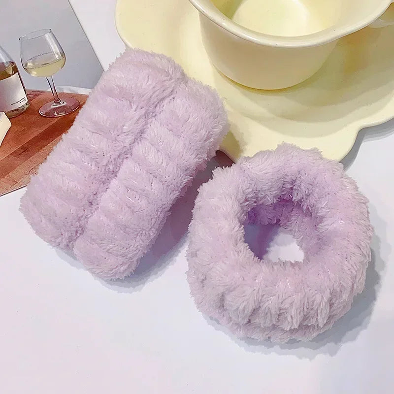 A fluffy lavender microfiber wrist sweatband and scrunchies are displayed next to a bowl of cream.