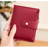 A hand holds a deep red textured leather bifold wallet with a flap closure.