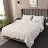 A white 3D pinch pleated duvet cover set displayed on a bed with gray upholstered headboard.