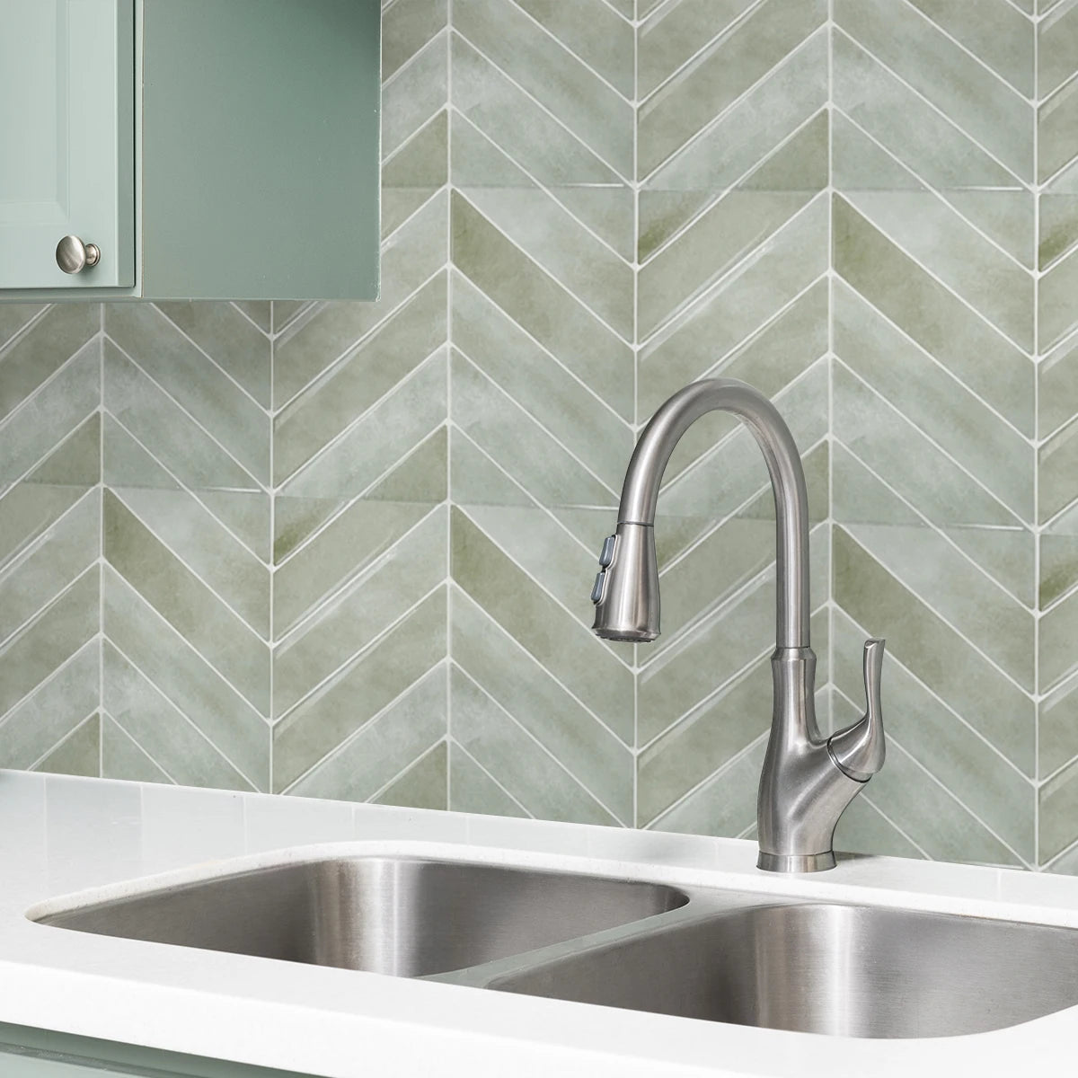 A modern kitchen sink and faucet are visible against a light green diagonal tile backsplash.