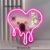 A neon sign shaped like a melting heart illuminates a pink and purple liquid effect on a white table.