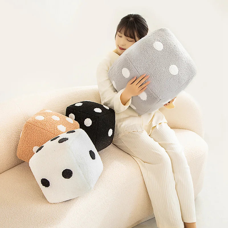 A woman is holding a large, gray and white polka-dotted plush pillow on her lap.