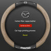 A round steering wheel cover made of tan carbon fiber nappa leather with a silver Mazda logo printing process.