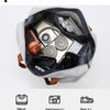 A gray travel duffle bag is shown open, displaying various items like a camera, toiletries, and clothing for short-distance t