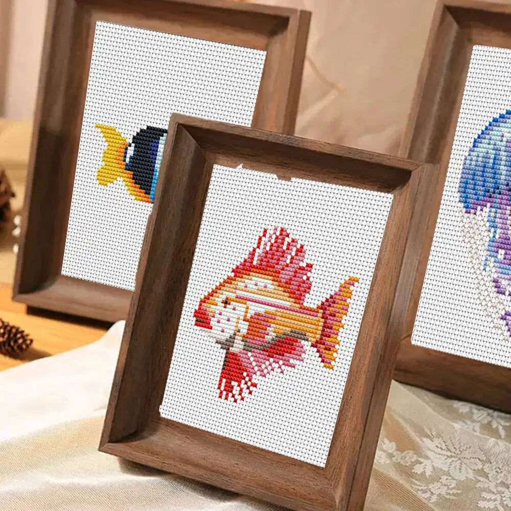A set of twelve framed cross stitch kits featuring colorful sea life animals in wooden frames.