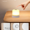 A white rechargeable night light is shown on a wooden table, with close-ups of its components: a charging port, a touch switc