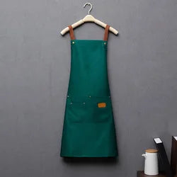 A dark green waterproof kitchen apron hanging on a wooden hanger against a gray wall.