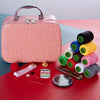 A pink faux leather sewing kit with a handle, including various colored thread spools and a pair of scissors on a red surface