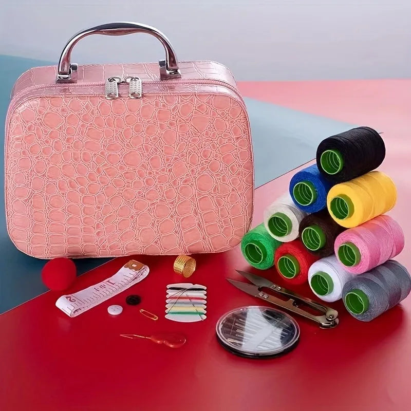 A pink faux leather sewing kit with a handle, including various colored thread spools and a pair of scissors on a red surface