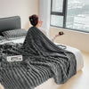 A dark gray plush cozy fleece blanket draped over a person sitting by a window.