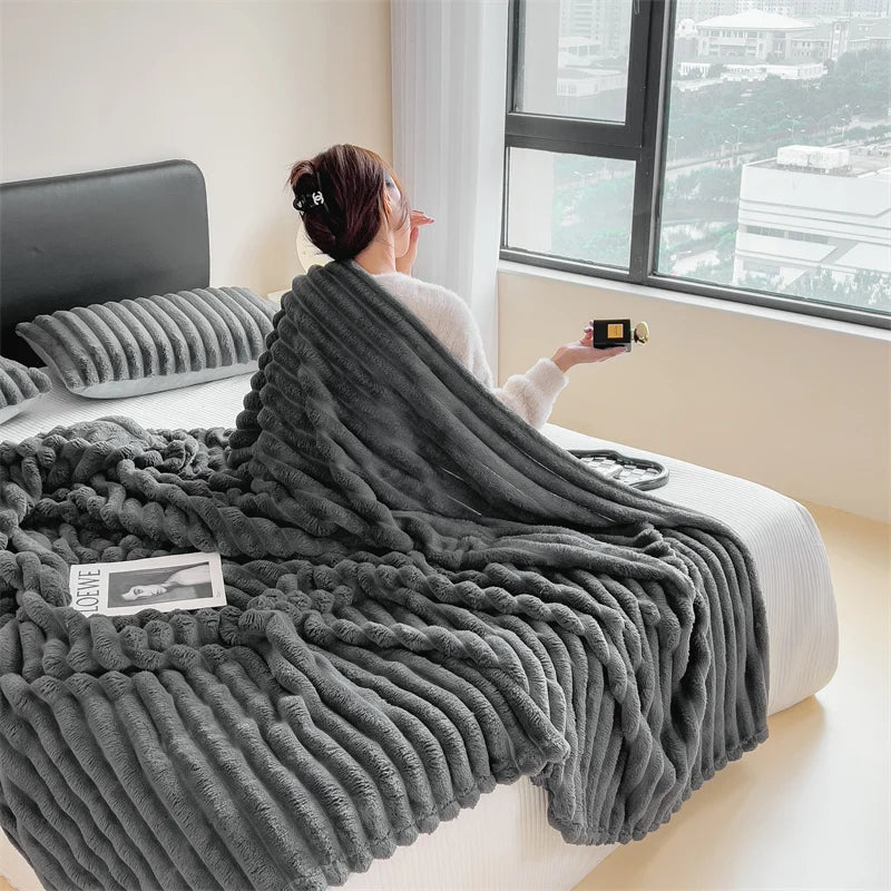 A dark gray plush cozy fleece blanket draped over a person sitting by a window.